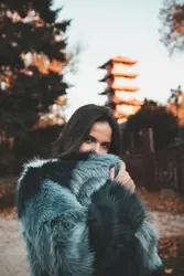 Woman in gray and black fur coat standing